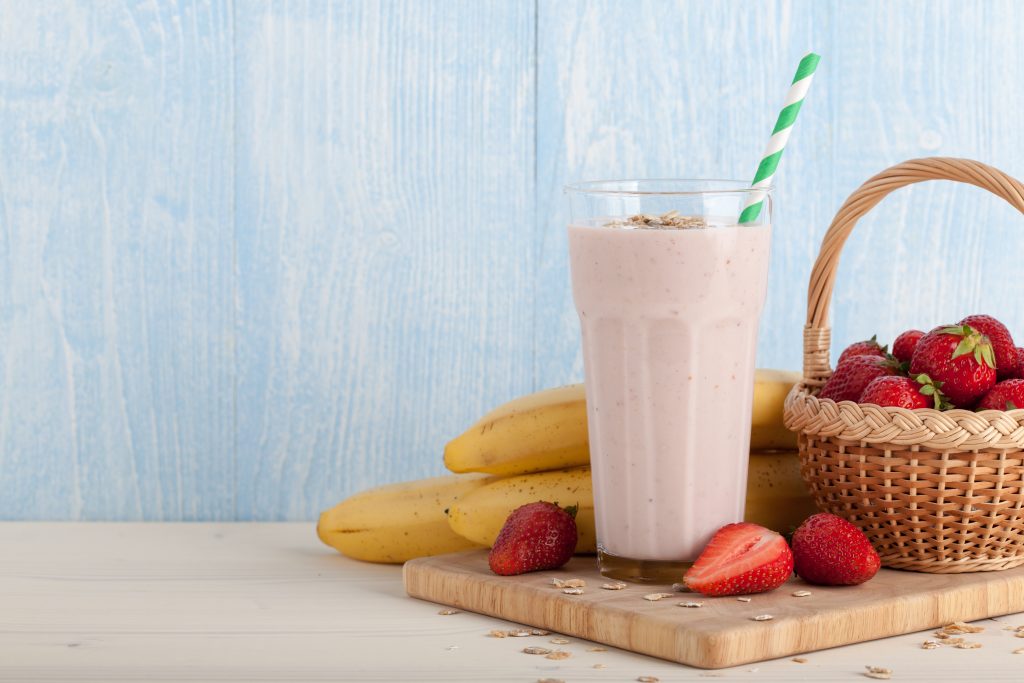 batido con mantequilla de maní en un vaso con bananas y frutillas