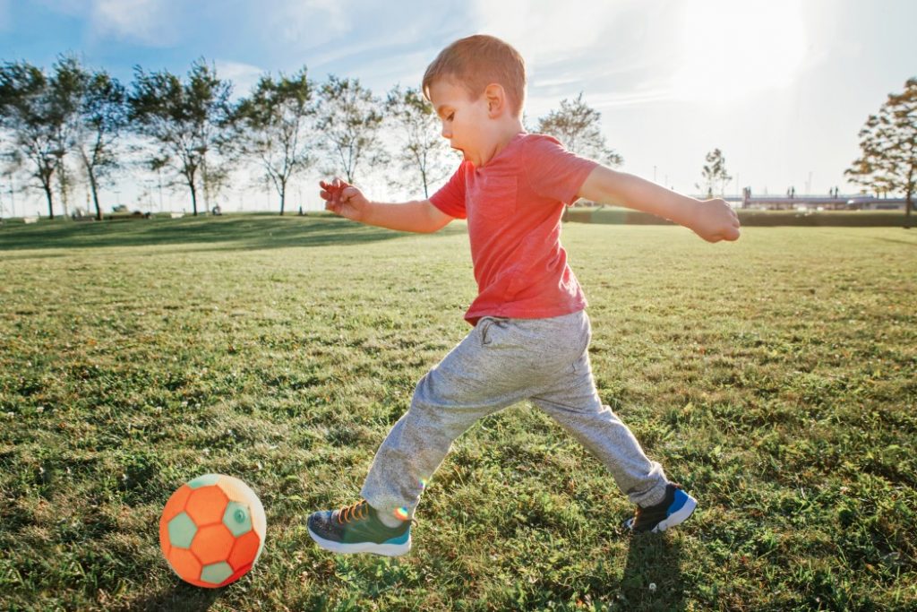 Niño jugando futbol en el césped